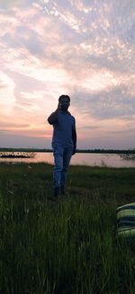 Man standing on field against sky during sunset