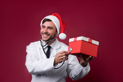 Portrait of smiling young man wearing hat against red background