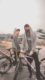 Young man sitting on bicycle against clear sky