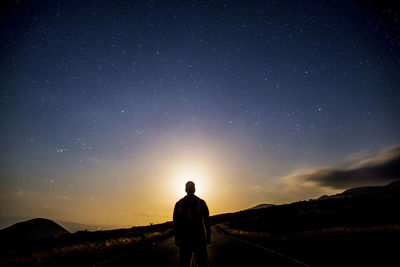 Silhouette man standing on field against sky during sunset