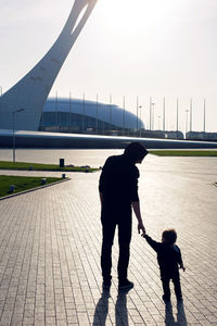 Child walks with his father in the park on the square in sochi in silhouettes