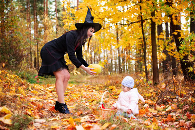 Low angle view of child playing in forest during autumn