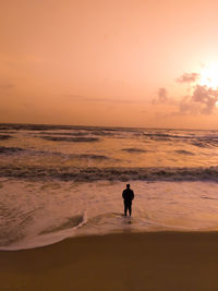 Silhouette of men on beach against sky during sunset