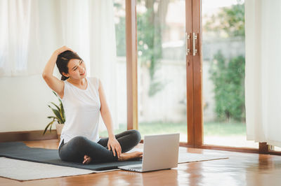 Young woman using phone while sitting on floor at home