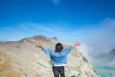 Rear view of woman standing on rock