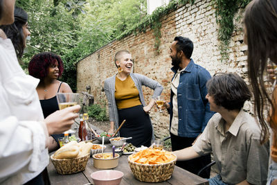 Young woman with hand on hip talking to friends during social gathering in back yard
