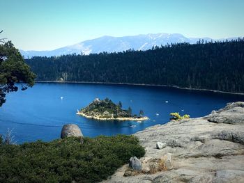 Scenic view of lake and mountains against clear blue sky