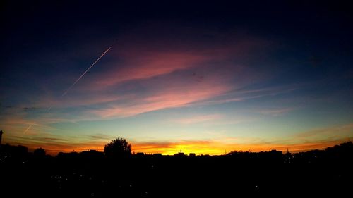 Silhouette trees against dramatic sky during sunset