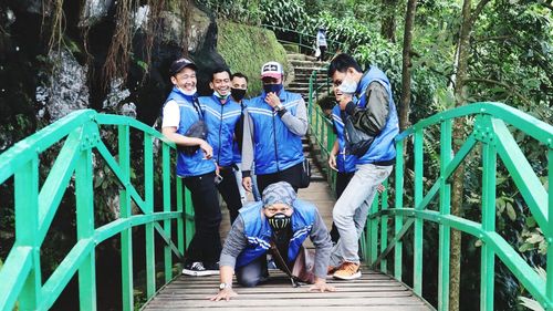 People standing on footbridge in forest