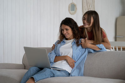 Young woman using laptop while sitting on sofa at home