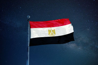 Low angle view of egyptian flag against star field sky