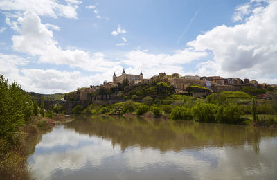 Scenic view of river by buildings against sky