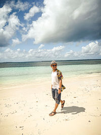 Rear view of woman standing at beach against sky