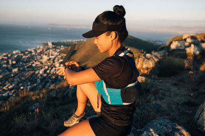 Side view of woman sitting on rock