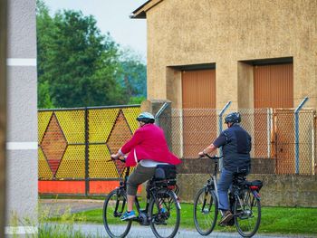 Rear view of men riding bicycle on street against building