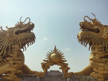 Low angle view of statue against temple building against sky