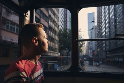 Portrait of young man looking through window