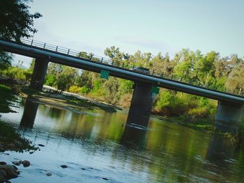 Bridge over river in forest against sky