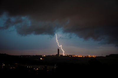 Illuminated factory against sky at night
