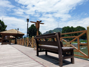 Empty benches and table by building against sky