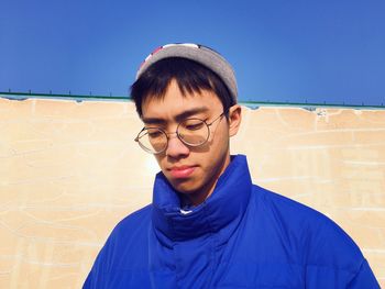 Portrait of young man standing against blue sky