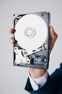 Close-up of hand holding camera against white background