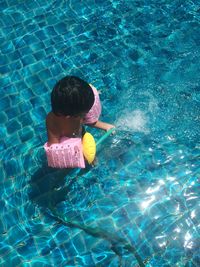 High angle view of boy holding hose in swimming pool