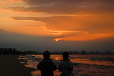 Rear view of silhouette woman standing against sky during sunset