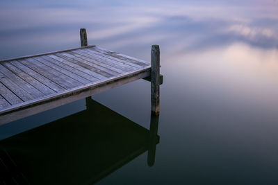 Wooden pier on lake against sky