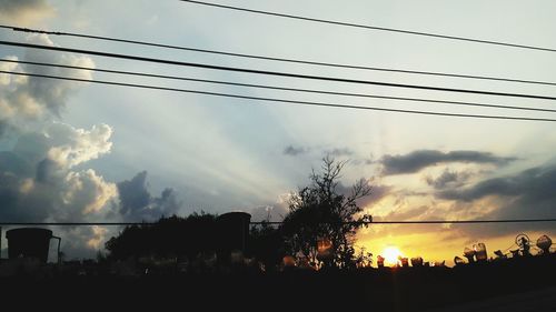 Low angle view of power lines against cloudy sky