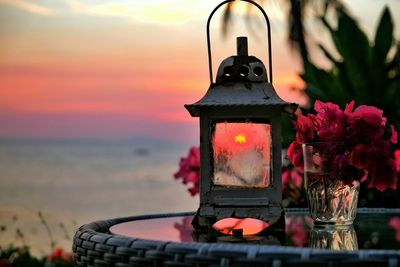 Lantern with bougainvillea on table during sunset