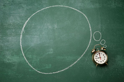 Directly above shot of alarm clock with speech bubble on blackboard