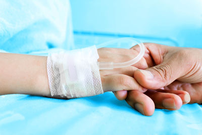 Close-up of hand holding patient at hospital bed
