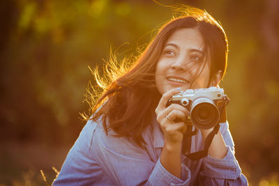 Close-up of smiling young woman holding camera