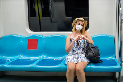 Portrait of woman wearing mask making heart shape in train
