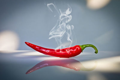 Smoke coming out from red chili pepper on glass table