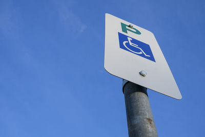 Low angle view of road sign against clear blue sky