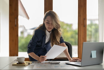 Young woman using laptop while sitting on table