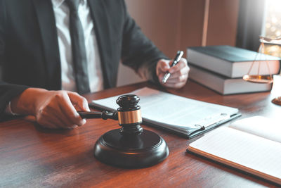 Midsection of man reading book on table