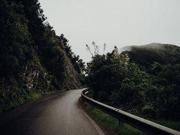 Road amidst trees against clear sky