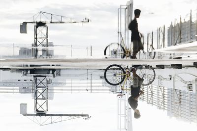 Man with bicycle against sky