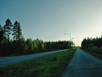 Road amidst trees against clear sky