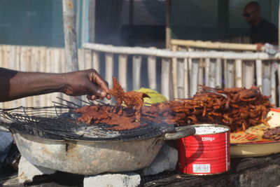 Midsection of person preparing food on barbecue grill