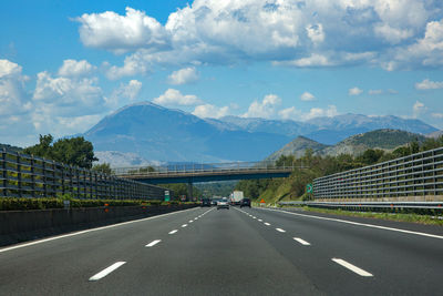 Road by mountains against sky