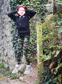 Full length of teenage girl standing by tree in forest