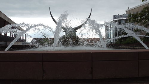 Water fountain in swimming pool against sky