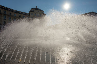 Water splashing on street against buildings in city