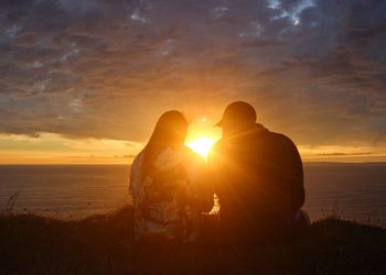 Rear view of couple against sky during sunset