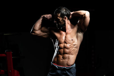 Portrait of shirtless man exercising in gym