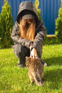 A teenage girl holds a cat on the street.